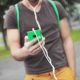 Teenage boy walking with handheld device with earphones attached. Image is just of his torse
